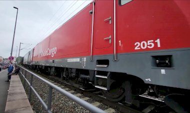 Локомотив из трех секций тянет тяжелый состав цистерн.