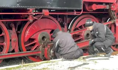 Рабочие производят обслуживание колёсной пары у паровоза на стоянке в депо